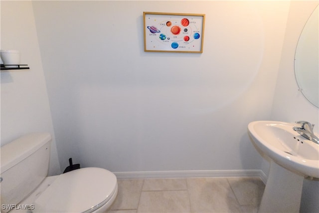 bathroom featuring toilet, tile patterned floors, and sink