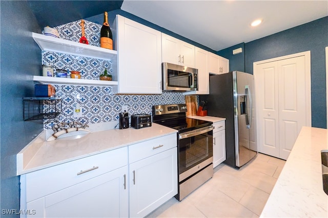 kitchen with decorative backsplash, white cabinets, and appliances with stainless steel finishes