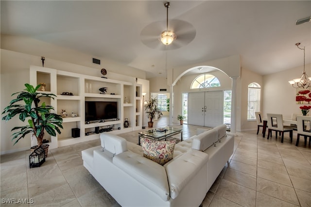 living room with light tile patterned floors, ceiling fan with notable chandelier, built in features, and ornate columns