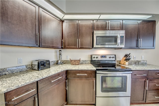 kitchen with dark brown cabinets, light stone counters, and appliances with stainless steel finishes