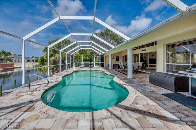 view of pool featuring outdoor lounge area, ceiling fan, glass enclosure, a patio area, and a water view