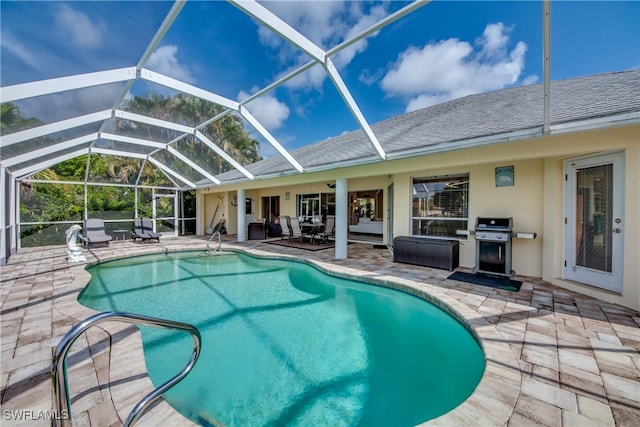 view of pool featuring a patio, glass enclosure, and grilling area