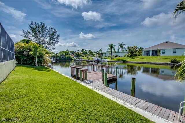 dock area with a yard, a water view, and glass enclosure