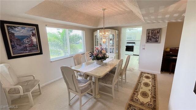 carpeted dining space with a tray ceiling, a textured ceiling, and a notable chandelier