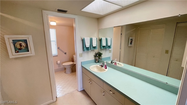 bathroom featuring tile patterned flooring, vanity, a skylight, and toilet