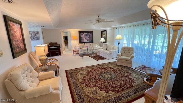 carpeted living room featuring ceiling fan and a textured ceiling