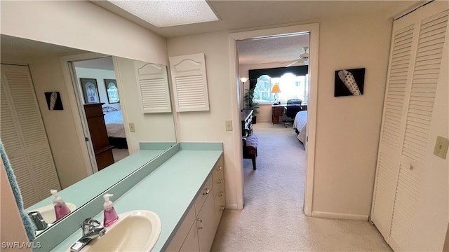 bathroom featuring ceiling fan, vanity, and a textured ceiling