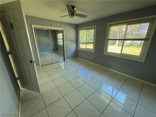 unfurnished bedroom featuring light tile patterned flooring, ceiling fan, and a closet