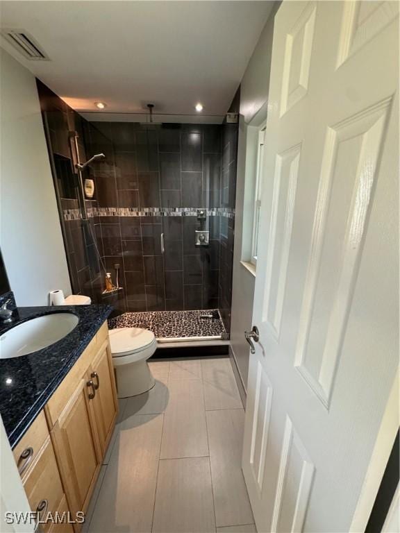 bathroom with a tile shower, vanity, and toilet