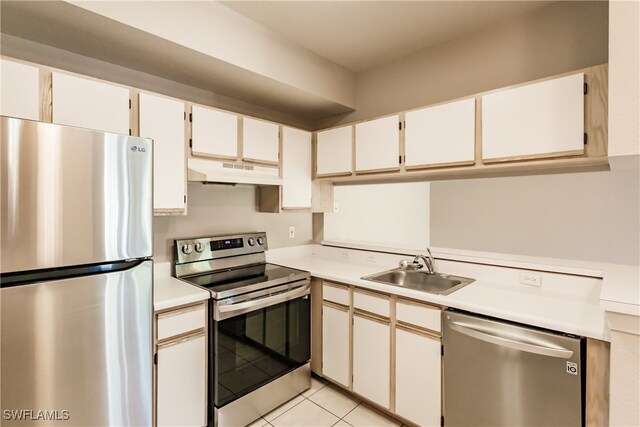 kitchen with light tile patterned flooring, appliances with stainless steel finishes, white cabinetry, and sink