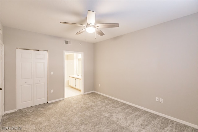 unfurnished bedroom with connected bathroom, ceiling fan, a closet, and light carpet