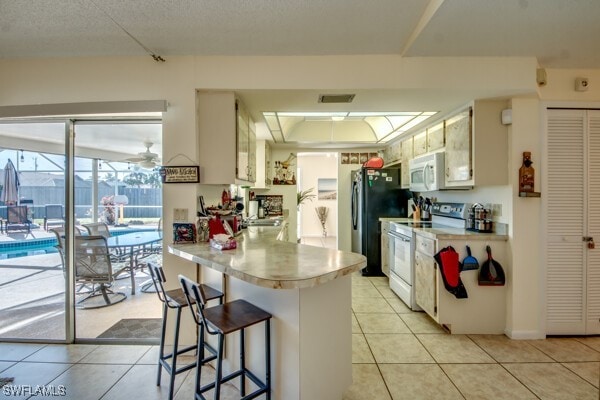 kitchen with ceiling fan, white appliances, kitchen peninsula, and light tile patterned floors