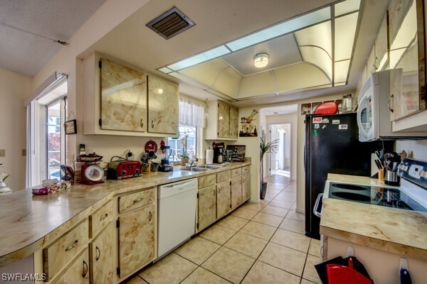 kitchen with a wealth of natural light, sink, light tile patterned flooring, and white appliances