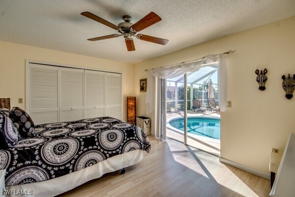 bedroom with a textured ceiling, access to outside, ceiling fan, light hardwood / wood-style floors, and a closet