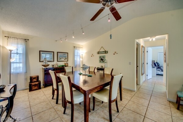 tiled dining space with ceiling fan and lofted ceiling