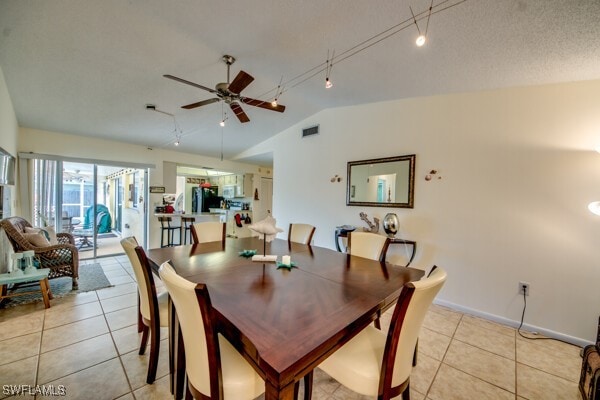 dining area featuring ceiling fan, a textured ceiling, track lighting, lofted ceiling, and light tile patterned flooring