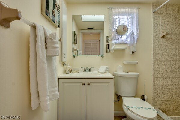 bathroom featuring tiled shower, vanity, and toilet