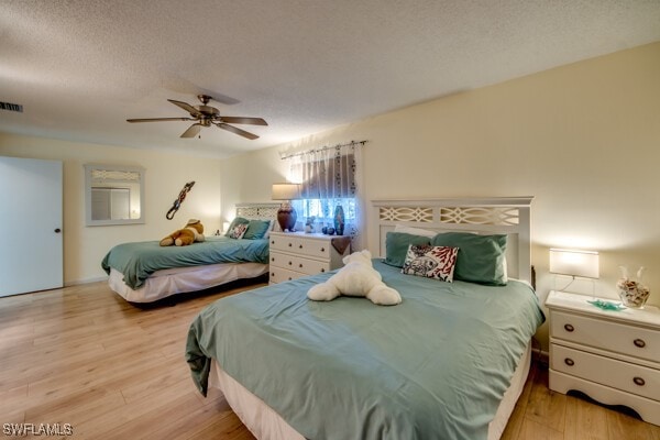 bedroom with ceiling fan, light hardwood / wood-style floors, and a textured ceiling