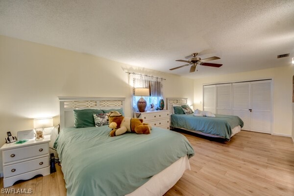 bedroom featuring ceiling fan, light wood-type flooring, a textured ceiling, and a closet