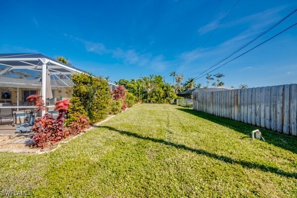 view of yard with glass enclosure and a patio