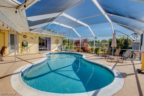 view of swimming pool with glass enclosure and a patio area