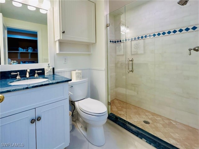 bathroom with tile patterned flooring, vanity, toilet, and a shower with shower door