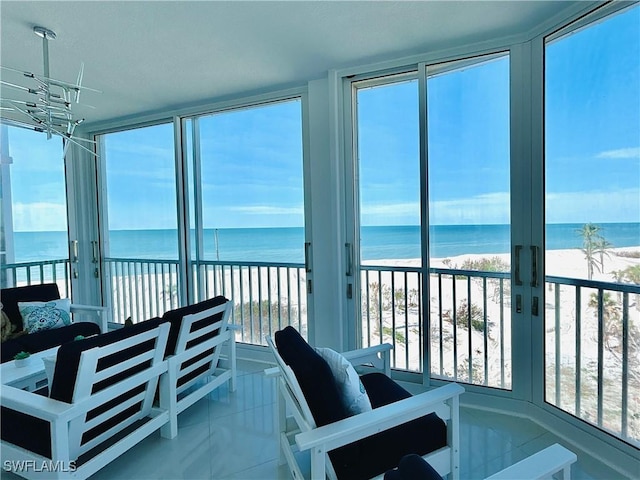 sunroom / solarium featuring a beach view, a water view, and a wealth of natural light