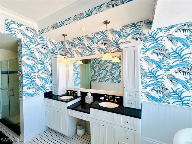 bathroom featuring a textured ceiling, vanity, a shower with shower door, and ornamental molding