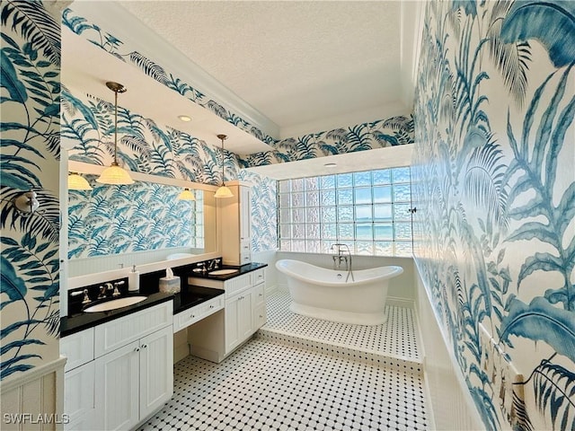 bathroom featuring a bathing tub, vanity, and a textured ceiling