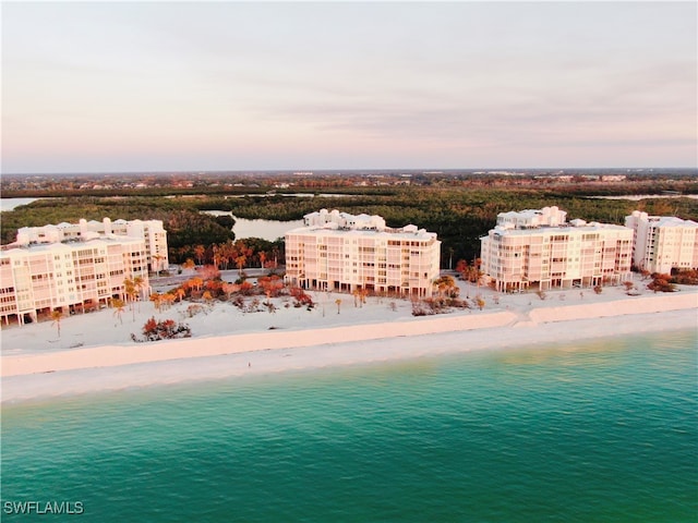 aerial view at dusk with a beach view and a water view