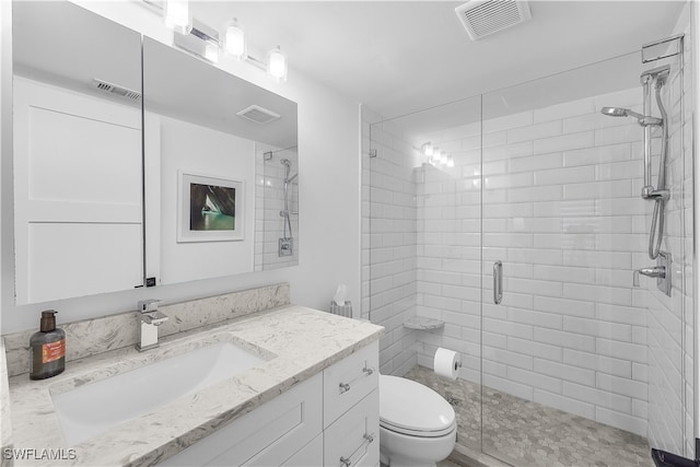 bathroom featuring a shower with door, vanity, and toilet