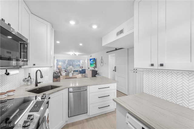 kitchen featuring sink, stainless steel appliances, tasteful backsplash, white cabinets, and a barn door