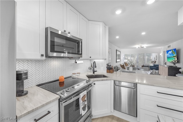 kitchen featuring sink, light stone counters, stainless steel appliances, decorative backsplash, and white cabinets