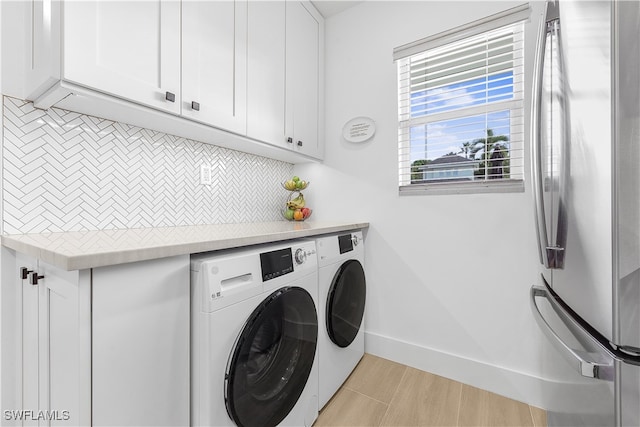 washroom featuring cabinets, washing machine and clothes dryer, plenty of natural light, and light hardwood / wood-style floors