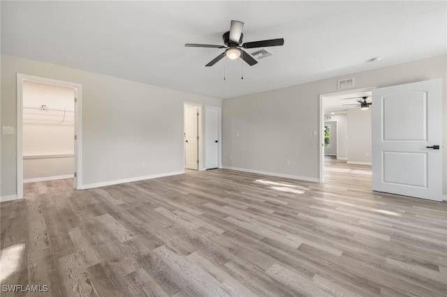 empty room with ceiling fan and light hardwood / wood-style flooring