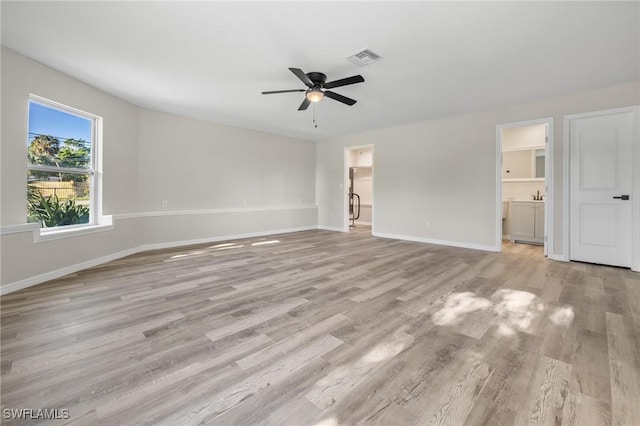 interior space with ensuite bath, ceiling fan, light hardwood / wood-style floors, and a walk in closet