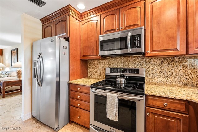 kitchen featuring light stone countertops, decorative backsplash, and stainless steel appliances