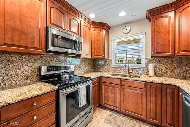 kitchen with sink, light tile patterned floors, stainless steel appliances, and light stone countertops