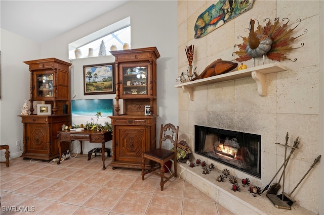 living area with lofted ceiling, light tile patterned floors, and a tiled fireplace