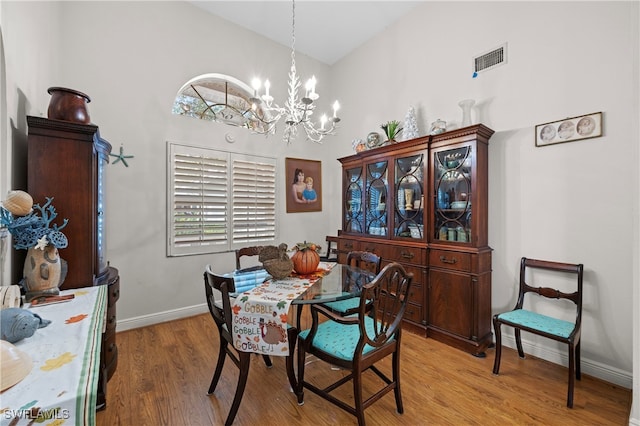 dining area featuring a notable chandelier, a healthy amount of sunlight, a high ceiling, and light hardwood / wood-style flooring