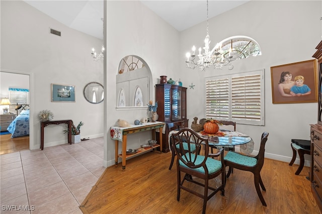 dining room with a notable chandelier, light wood-type flooring, and high vaulted ceiling