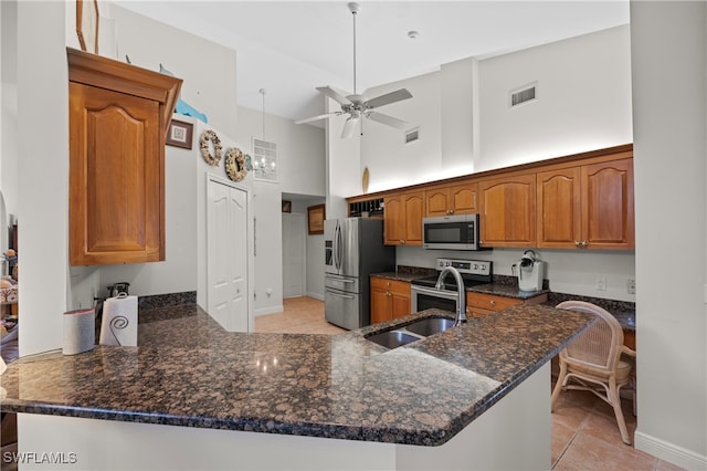 kitchen with kitchen peninsula, appliances with stainless steel finishes, high vaulted ceiling, and ceiling fan