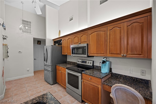 kitchen with hanging light fixtures, stainless steel appliances, an inviting chandelier, a towering ceiling, and light tile patterned floors