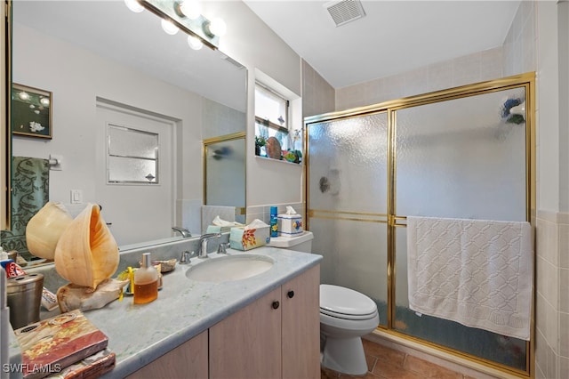 bathroom featuring vanity, tile patterned flooring, toilet, tile walls, and walk in shower