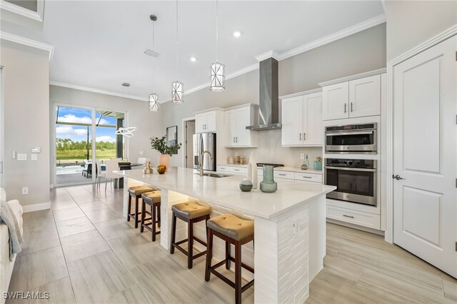 kitchen featuring decorative light fixtures, an island with sink, sink, white cabinets, and a kitchen breakfast bar