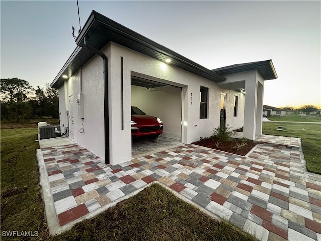 property exterior at dusk with a lawn and cooling unit