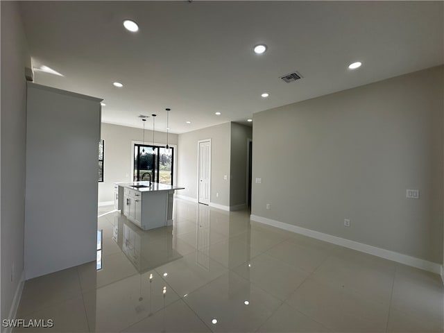 kitchen featuring sink, pendant lighting, a center island with sink, white cabinetry, and light tile patterned flooring