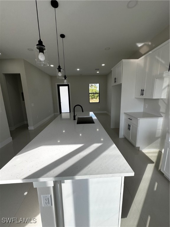 kitchen featuring white cabinetry, sink, a spacious island, and decorative light fixtures