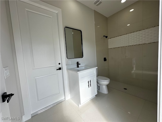 bathroom featuring tile patterned floors, vanity, a tile shower, and toilet