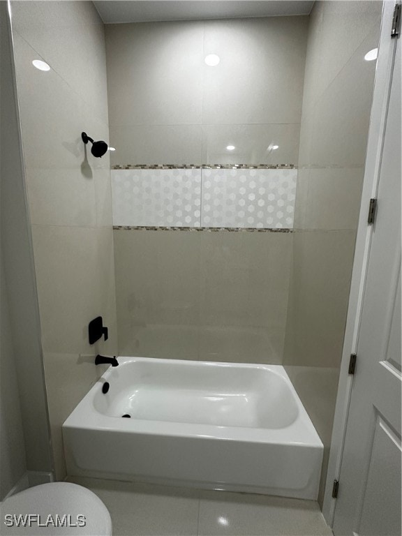 bathroom with toilet and tiled shower / bath